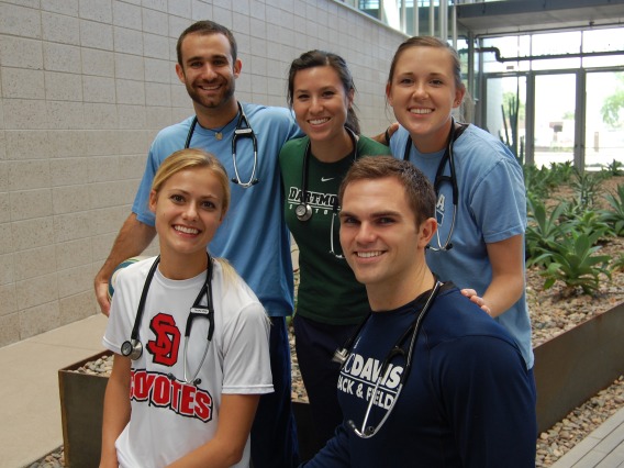A group of five students smiling at the camera, each wearing a stethoscope around their neck.